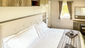 A bedroom with a bed, a bedside table, a mirror, and a window with curtains. - 1 bedroom accommodation in Tunstall, Nr Hull (Tunstall, Nr Hull)
