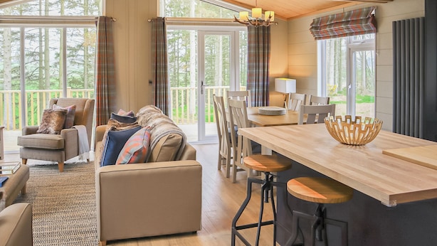 A spacious room with a large window, a sofa, a dining table with chairs, and a bar area. - 3 bedroom accommodation in Lauder (Lauder)