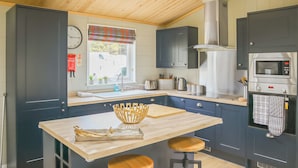 A modern kitchen with dark cabinets, a wooden countertop, a built-in oven, and a window with a view of the outside. - 3 bedroom accommodation in Lauder (Lauder)
