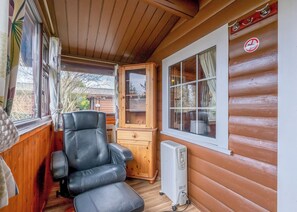 A cozy cabin interior with a leather chair, a wooden cabinet, and a radiator.