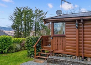 A wooden cabin with a satellite dish, a window, and a porch with steps.