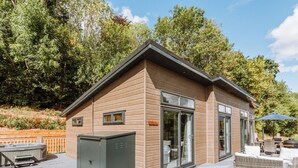 Une cabane moderne en bois, dotée d’une terrasse, d’un bain à remous et de mobilier d’extérieur.
