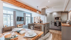 Une cuisine moderne avec un coin repas, un plafond en bois et de grandes fenêtres.