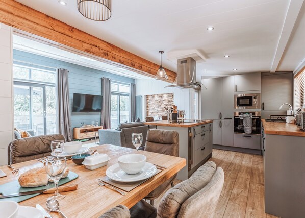 Een moderne keuken met een eethoek, houten plafond en grote ramen.