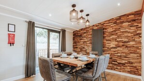 Un coin repas avec une table en bois, quatre chaises et un luminaire moderne.