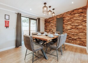 A dining area with a wooden table, four chairs, and a modern light fixture.