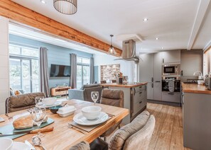 Una cocina moderna con comedor, techo de madera y ventanas amplias.