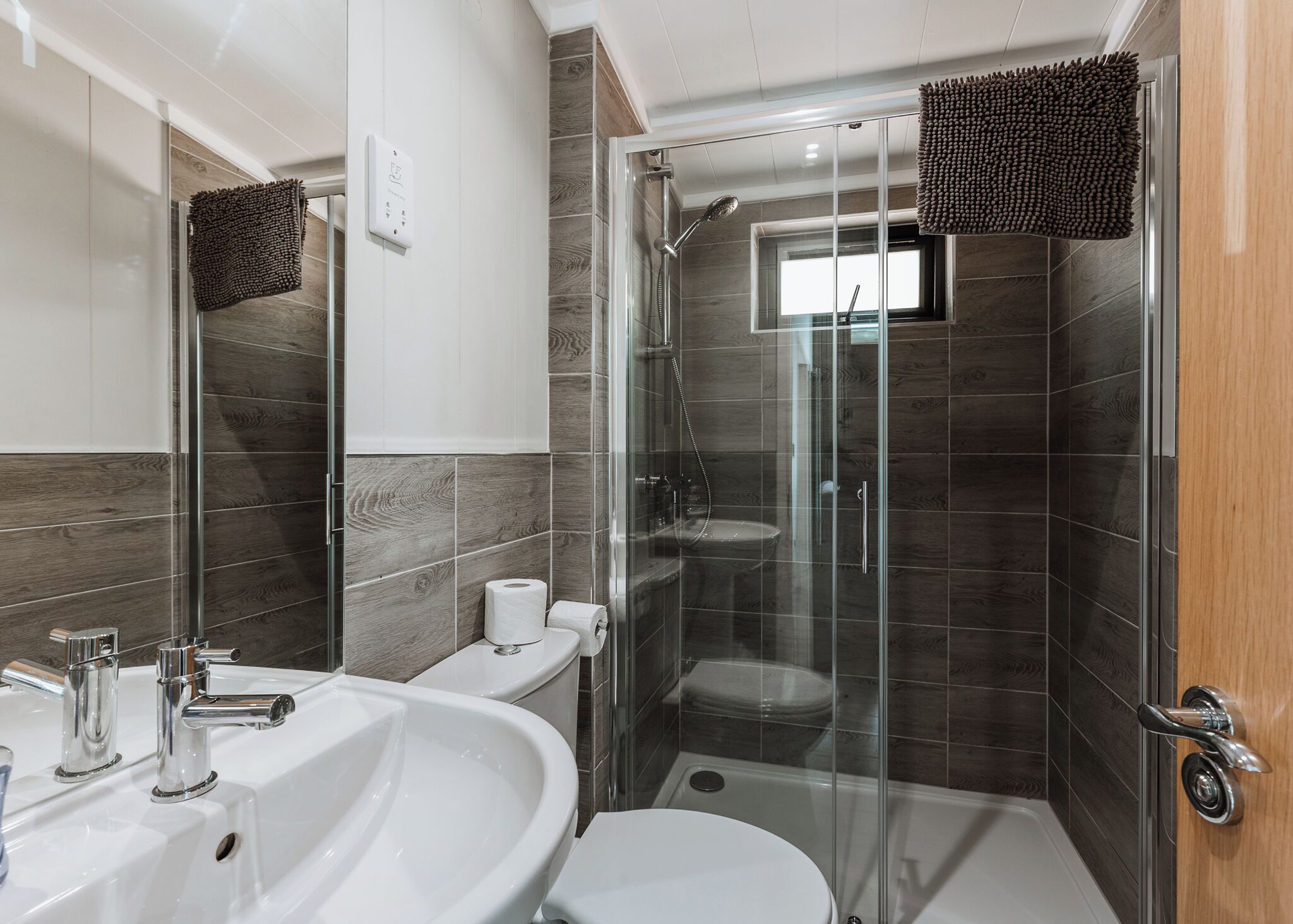 A modern bathroom with a glass-enclosed shower, a white sink, and a toilet.