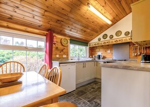 Un interior de madera con cocina, mesa de comedor, sillas y vistas al exterior.