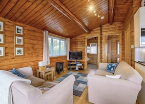 L’intérieur d’une cabane en rondins comprend un salon, un téléviseur et un coin cuisine.