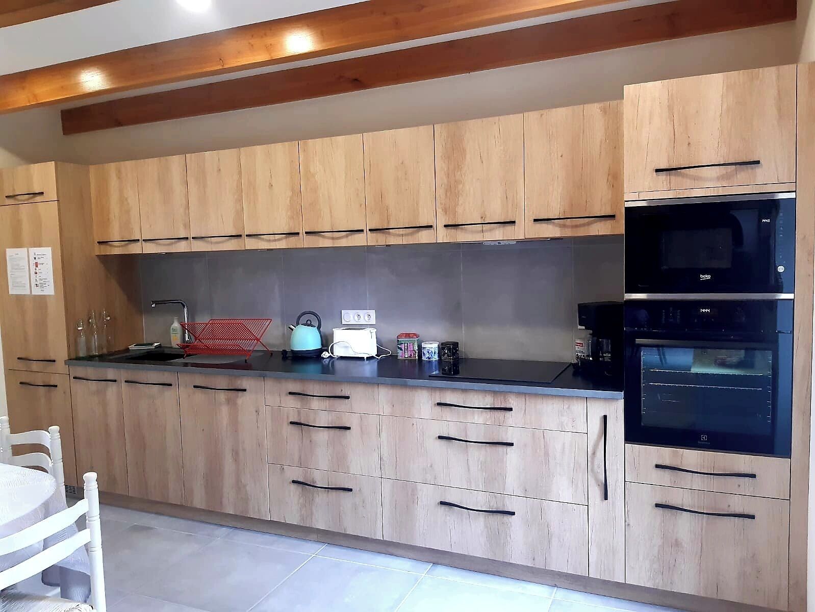 A kitchen with wooden cabinets, a black countertop, a kettle, a toaster, and a coffee maker.