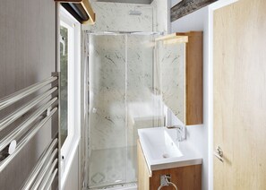 A modern bathroom with a glass shower enclosure, a wooden vanity, and a white sink.
