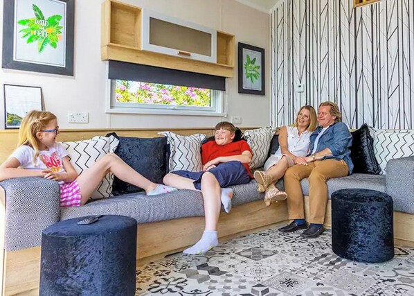 Un salon comprenant un canapé, des poufs, une fenêtre avec vue et des œuvres d’art murales.