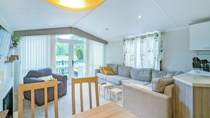 A modern living room with a sofa, chairs, a dining table, and a kitchen area. - 2 bedroom accommodation in Carnforth (Carnforth)