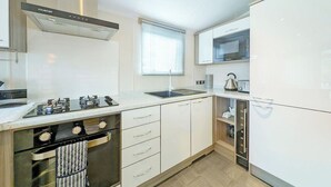 A modern kitchen with white cabinetry, a gas stove, a built-in oven, a microwave, and a sink. - 2 bedroom accommodation in Carnforth (Carnforth)