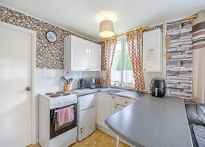 Eine kompakte Küche mit Herd, Backofen, Mikrowelle und Kaffeemaschine.