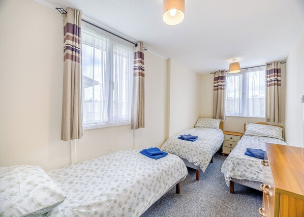 A room with two single beds, a wooden desk, and a window with curtains. - 2 bedroom accommodation in Anderby Creek, Mablethorpe (Anderby Creek, Mablethorpe)