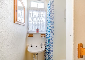 Ein Badezimmer mit Fenster, Waschbecken und Duschvorhang.