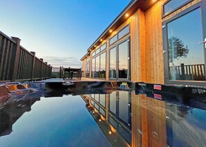 A modern building with large windows, a wooden exterior, and a reflective pool.