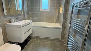 A modern bathroom with a white vanity, a bathtub, and a glass shower enclosure.