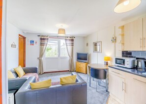 A compact living space with a sofa, a television, a small table, and a kitchenette.