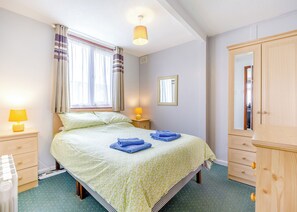 A bedroom with a bed, bedside lamps, a mirror, and a wardrobe.