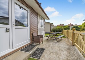 A residential property with a garage door, a patio with a picnic table and chairs, and a wooden fence.