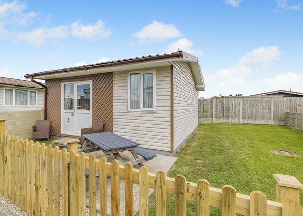 A single-story mobile home with a patio, a fenced yard, and a wooden deck.