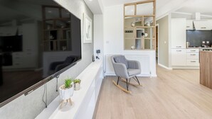 Una sala moderna con un televisor de pantalla plana grande, un sillón mecedor y una estantería empotrada de madera con adornos.