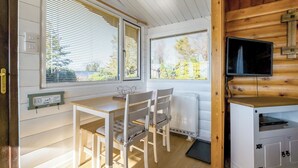 Interior de una cabaña con una mesa de comedor, sillas, un televisor y un letrero que indica una playa que admite perros.
