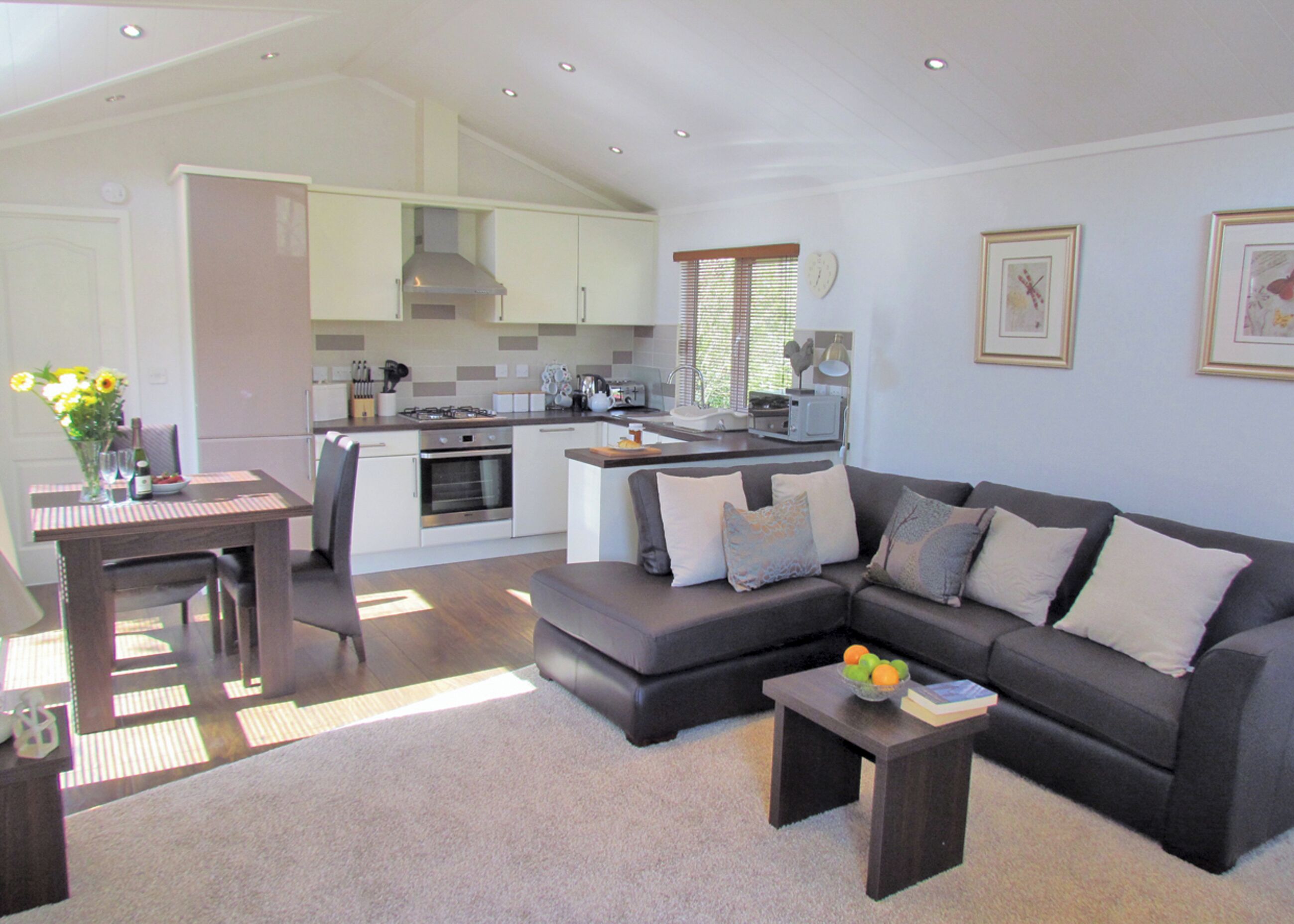 A modern living room with a grey sectional sofa, a coffee table, and a dining area with a table and chairs.