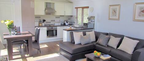 A modern living room with a grey sectional sofa, a coffee table, and a dining area with a table and chairs.