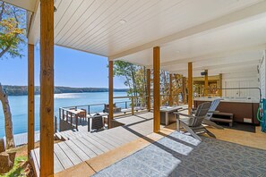 Eine Holzterrasse mit Sitzgelegenheiten im Freien, einem Whirlpool und Blick auf einen See.