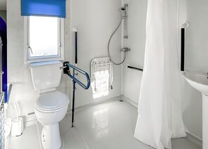Une salle de bain avec des toilettes, une douche, une fenêtre et un lavabo.