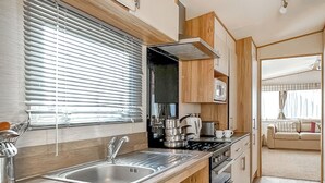 Pieni, käytännöllinen keittiö, jossa on pesuallas, liesi ja mikroaaltouuni.