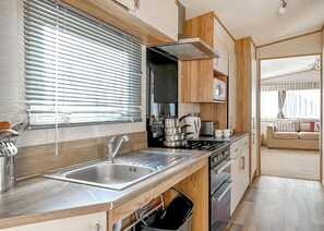 A compact kitchen with a sink, stove, and microwave.