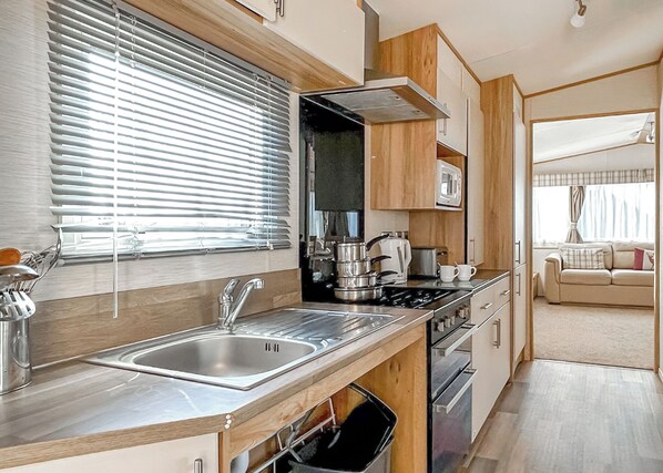 A compact kitchen with a sink, stove, and microwave.