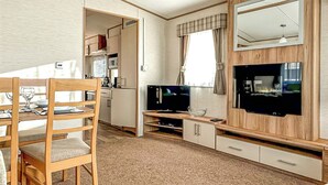Kompakti oleskelutila, jossa on ruokapöytä, televisio ja pieni keittiö.