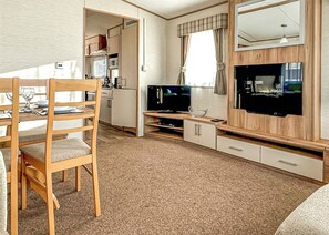 A compact living space with a dining table, TV, and kitchenette.