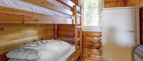 Une cabane équipée de lits superposés, d’un réfrigérateur et d’une fenêtre donnant sur la forêt.