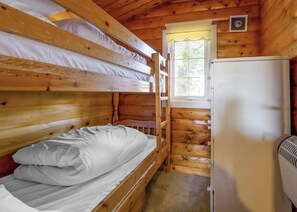 Eine Hütte mit Etagenbetten, einem Kühlschrank und einem Fenster mit Blick auf Bäume.
