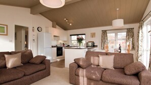 Een moderne woonkamer met twee bruine banken en een keuken op de achtergrond.