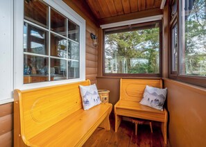 A wooden bench with a view of trees through a window.