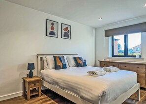 A modern hotel room with a large bed, bedside tables, a window with a view, and abstract wall art. - 2 bedroom accommodation in Old Buckenham (Old Buckenham)