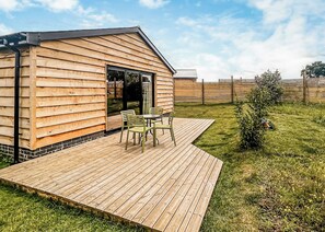 Eine Holzhütte mit einer Terrasse, einem Patio-Tisch und Stühlen.