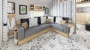 Ein modernes Wohnzimmer mit einer Eckcouch, einem Holztisch, einem Fernseher und einem gemusterten Boden.