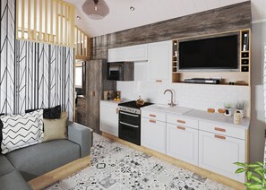 Une cuisine moderne avec des meubles blancs, une cuisinière noire et un grand téléviseur à écran plat.