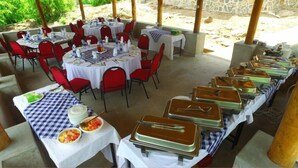 A covered outdoor dining area with round tables and red chairs, arranged in a semi-circle. - Mpale Cultural Village  (Mangochi)