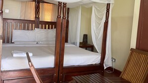 A wooden four-poster bed with a canopy, two wooden chairs, and a small table. - Mpale Cultural Village  (Mangochi)