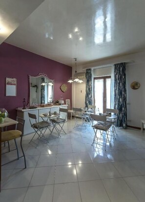 A spacious living area with a dining set, a large mirror, and a kitchen counter. - Il Sorriso Di Liu (Agrigento)